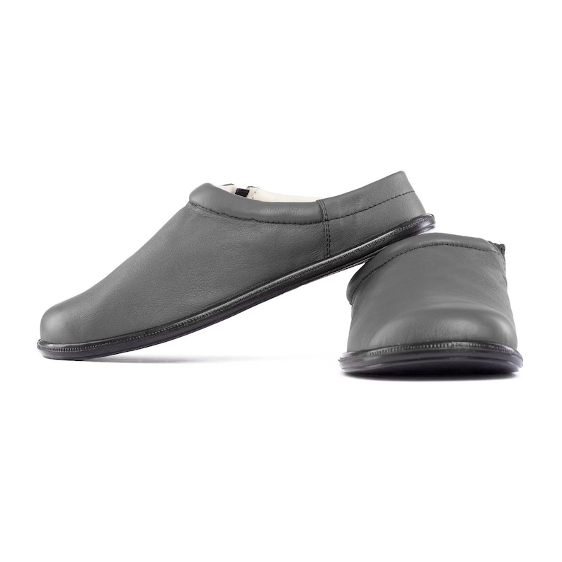 May include: A pair of gray leather slippers with a soft, comfortable lining. The slippers have a simple, classic design and are perfect for relaxing at home.