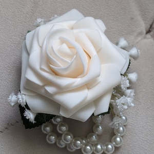 May include: A white silk rose with a pearl necklace, a popular choice for wedding bouquets or corsages.