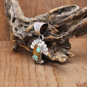 May include: A silver pendant with a turquoise stone set in a silver fan-shaped design. The pendant has a silver bail for attaching a chain.