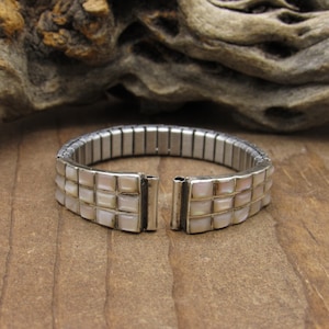 May include: A silver bracelet with a stretchy band and two rows of white mother-of-pearl squares.