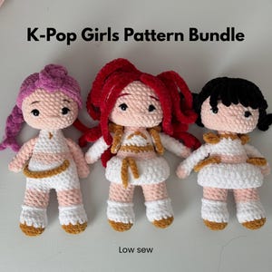 May include: Three handmade crochet dolls with different hair colors: pink, red, and black. Each doll wears a white outfit with gold accents. The text "K-Pop Girls Pattern Bundle" is at the top, and "Low sew" is at the bottom.