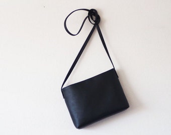 Minimalist black leather crossbody bag with magnetic closure