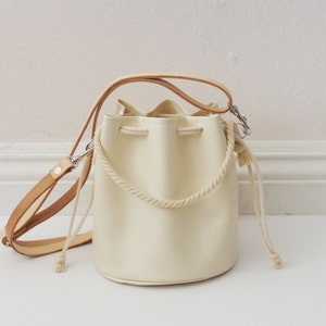 White faux leather drawstring crossbody bucket bag with veg tan leather straps