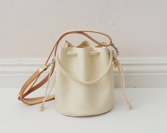 White faux leather drawstring crossbody bucket bag with veg tan leather straps