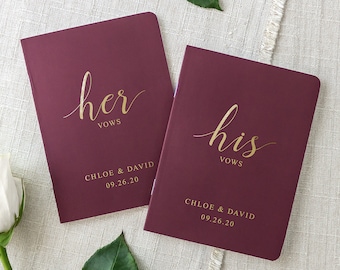 May include: Two burgundy vow books with gold lettering. The book on the left says "her vows" and the book on the right says "his vows". Both books have the names "Chloe & David" and the date "09.26.20" printed on them.