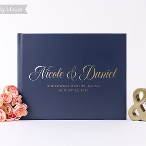 May include: Navy blue wedding guest book with gold lettering that reads "Nicole & Daniel" and "Southwest Harbor, Maine August 22, 2020".