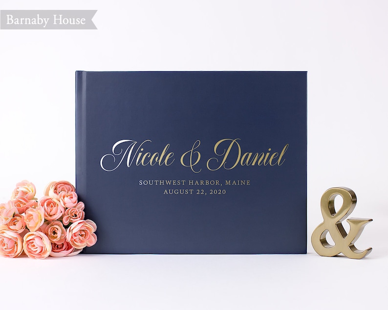 May include: Navy blue wedding guest book with gold lettering that reads "Nicole & Daniel" and "Southwest Harbor, Maine August 22, 2020".