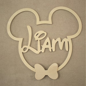 May include: Wooden cutout of Mickey Mouse ears with a bow tie and the name "Liam" in a stylized font.