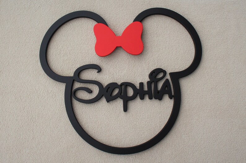 May include: Black wooden cutout of Mickey Mouse ears with a red bow and the name "Sophia" written in a stylized font.