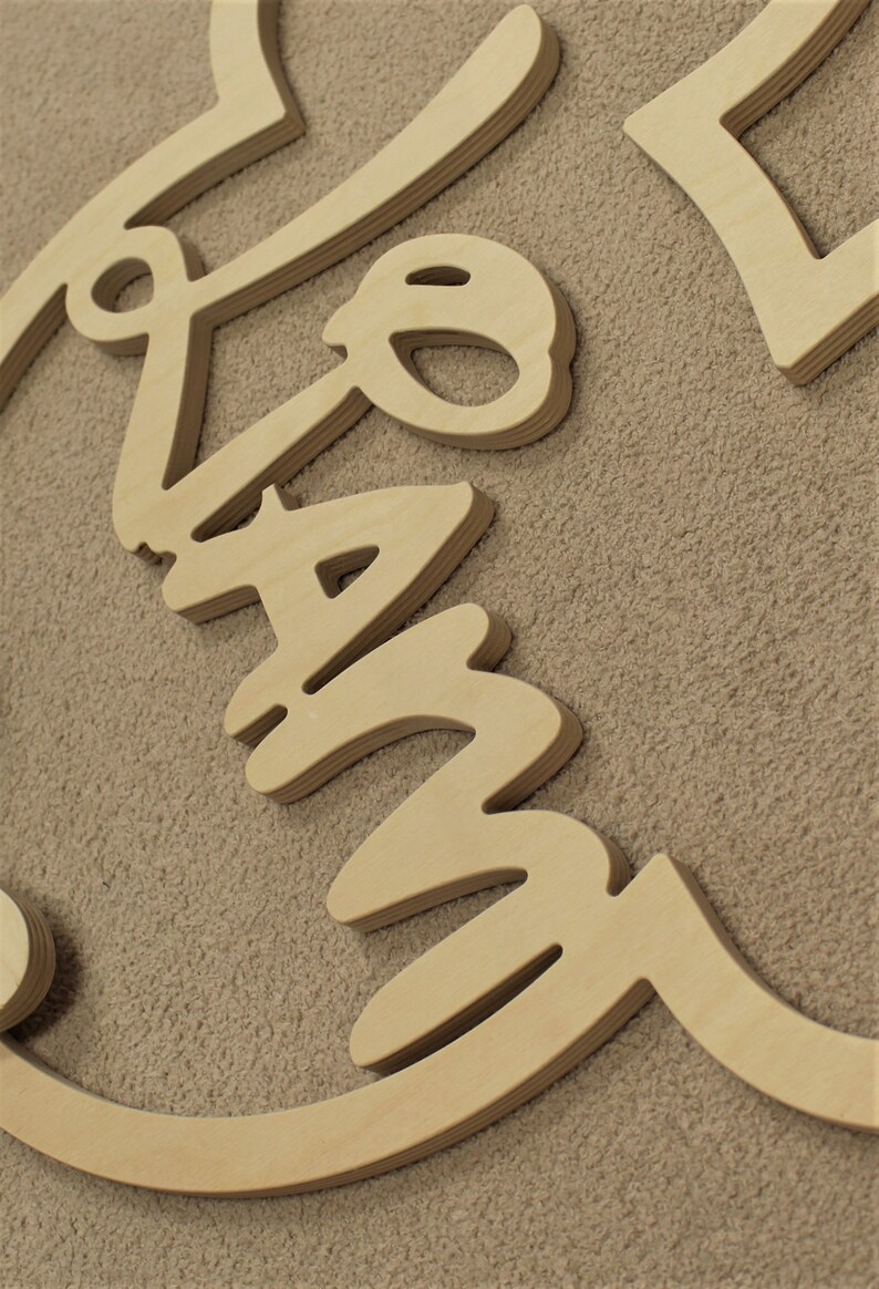 May include: Wooden sign with the word "Family" written in a cursive font. The sign is made of multiple layers of wood, giving it a 3D effect.
