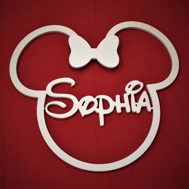 May include: White wooden cutout of Mickey Mouse ears with a bow in the center and the name "Sophia" written in a stylized font.