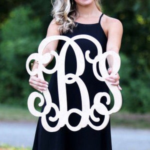 May include: A large, white wooden monogram with a cursive font. The monogram is in the shape of a circle with the letters "B" and "S" intertwined.