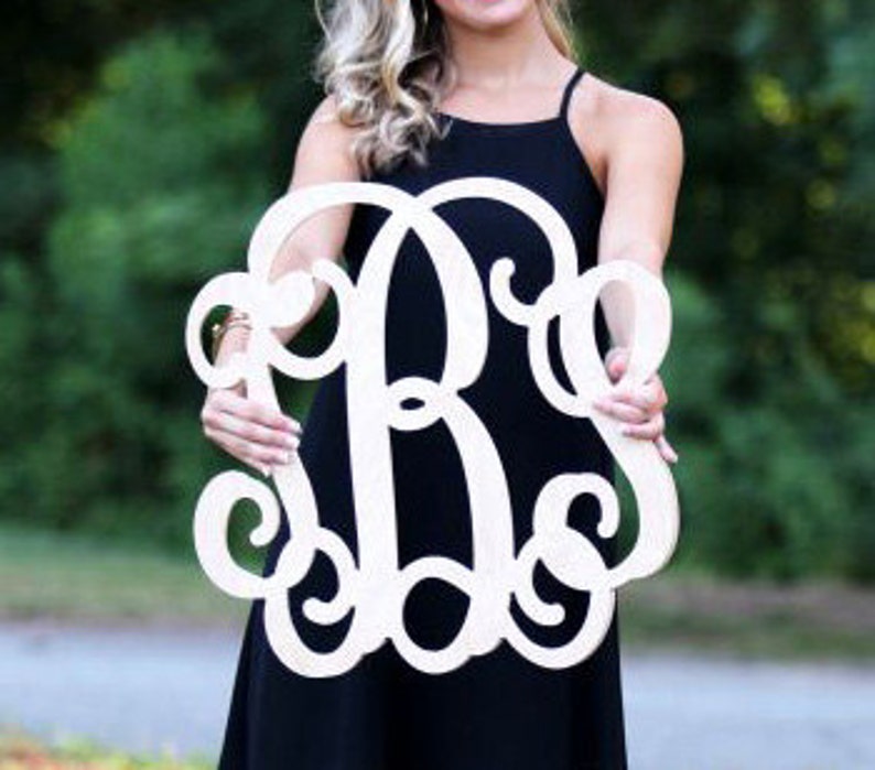 May include: A large, white wooden monogram with a cursive font. The monogram is in the shape of a circle with the letters "B" and "S" intertwined.