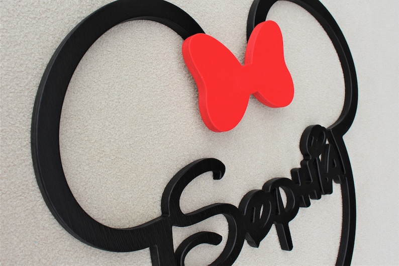 May include: Black wooden cutout of Mickey Mouse ears with a red bow and the name "Sophia" written in a stylized font.