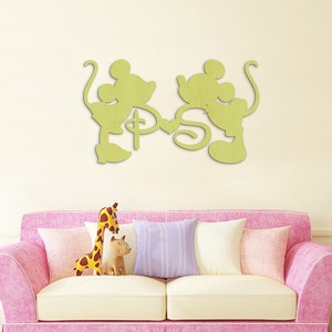 Puede incluir: Una decoraci&oacute;n de pared de madera con una silueta de Mickey Mouse y Minnie Mouse tom&aacute;ndose de la mano con las letras "P" y "S" en el medio. La decoraci&oacute;n est&aacute; pintada de color amarillo claro.