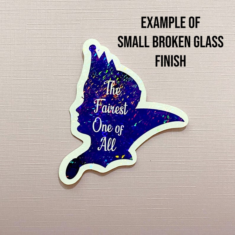 Puede incluir: Una silueta azul de una mujer con una corona, con el texto "The Fairest One of All" en blanco. La silueta est&aacute; hecha de un material brillante que se asemeja a vidrio roto.