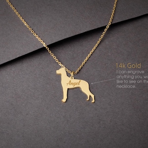 May include: A gold necklace with a dog silhouette pendant. The pendant is engraved with the name "Angel". The necklace is made of 14k gold. The text "14k Gold" is visible in the image. The text "I can engrave anything you would like to see on the necklace." is also visible in the image.
