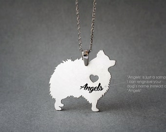 May include: Silver necklace with a pendant shaped like a Pomeranian dog. The pendant has a heart cut out and the name "Angels" engraved inside. The text "Angels is just a sample. I can engrave your dog's name instead of Angels" is also included in the image.