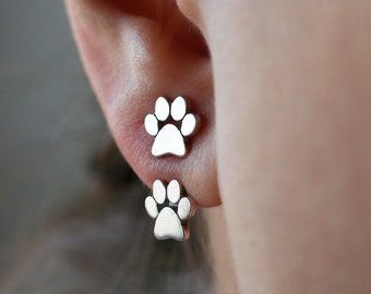 May include: A pair of silver paw print stud earrings. The earrings are small and delicate, and they would make a great gift for any dog lover.