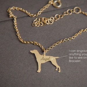 May include: Gold chain bracelet with a dog silhouette charm. The charm is engraved with the word "Angel".