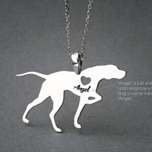 May include: Silver pendant necklace featuring a dog silhouette with a heart cutout. The name "Angel" is engraved inside the heart. "Angel" is just a sample, you can engrave your dog's name instead.