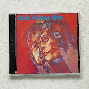 Puede incluir: Una caja de CD con la portada del álbum "Ssssh. Ten Years After". La carátula tiene un fondo rojo con una imagen superpuesta de un rostro en tonos morados y azules. El título del álbum está en texto azul.