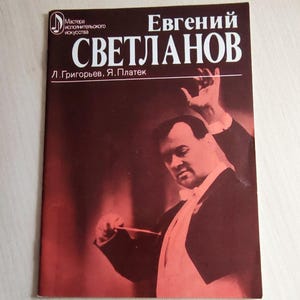 Op de afbeelding: Boekomslag met een portret van een man in smoking die dirigeert. De titel "Evgeniy Svetlanov" staat in witte letters. De achtergrond is donkerrood. Het is een biografie.