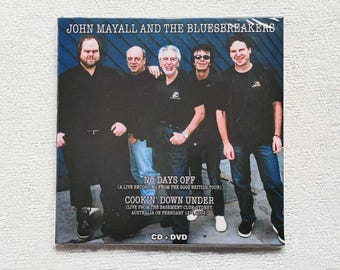 Puede incluir: CD + DVD de John Mayall and The Bluesbreakers. La portada del álbum presenta una foto grupal de la banda. El texto en la portada dice "NO DAYS OFF" y "COOKIN' DOWN UNDER" (Live from the Basement Club Sydney, Australia on February 12th, 2003).