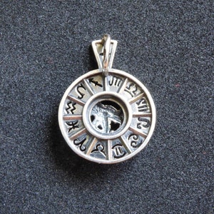 May include: Silver pendant featuring a circular design with the zodiac symbols around the edge. The center of the pendant has a cutout of a zodiac symbol.