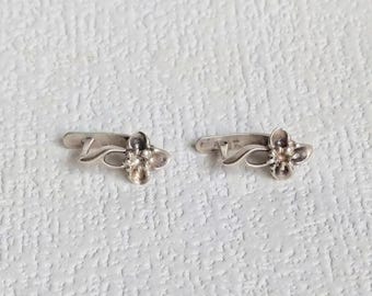 Puede incluir: Un par de pendientes de plata con un diseño floral. Los pendientes son pequeños y delicados, y serían un gran regalo para una ocasión especial.