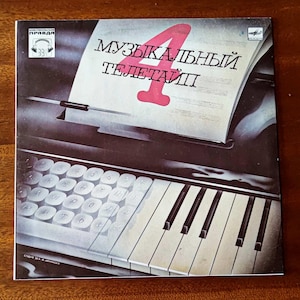 May include: Vintage vinyl record album cover featuring a stylized keyboard and sheet music. The title "Музыкальный Телетайп 4" is displayed in Russian with a large pink number 4. The album cover has a retro aesthetic.