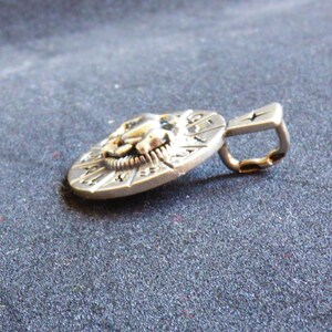 May include: Silver pendant with a detailed lion head design and a circular frame with engraved markings. The pendant has a loop for attaching a chain.