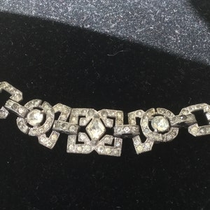 May include: A silver chain bracelet with a geometric design and clear rhinestones.