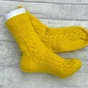May include: A pair of yellow knitted socks with a cable knit pattern.