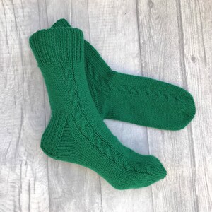 May include: A pair of green knitted socks with a cable knit pattern.