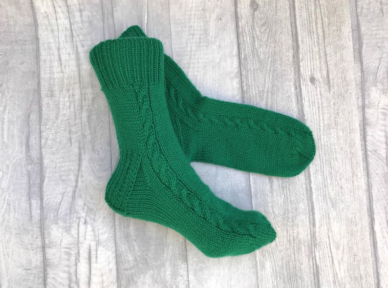 May include: A pair of green knitted socks with a cable knit pattern.