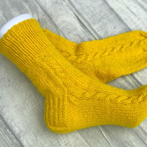 May include: A pair of yellow knitted socks with a cable knit pattern.