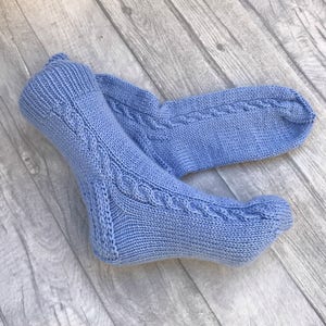 May include: A pair of blue knitted socks with a cable knit pattern.