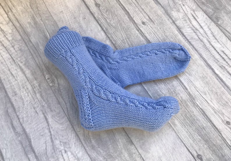May include: A pair of blue knitted socks with a cable knit pattern.