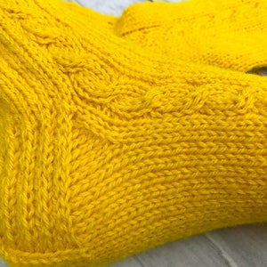 May include: A pair of yellow knitted socks with a cable knit pattern.
