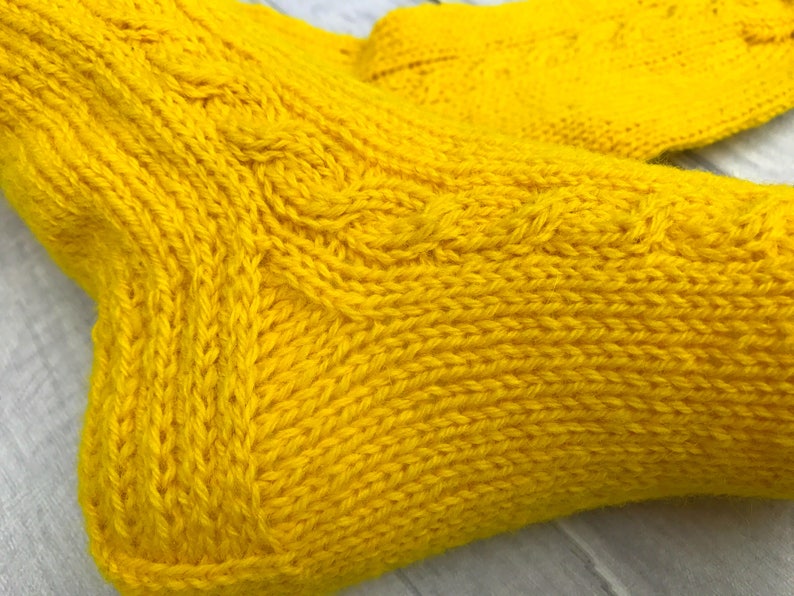 May include: A pair of yellow knitted socks with a cable knit pattern.