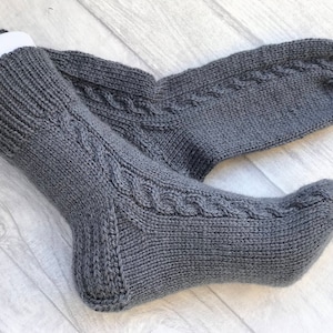 May include: A pair of gray knitted socks with a cable knit pattern.
