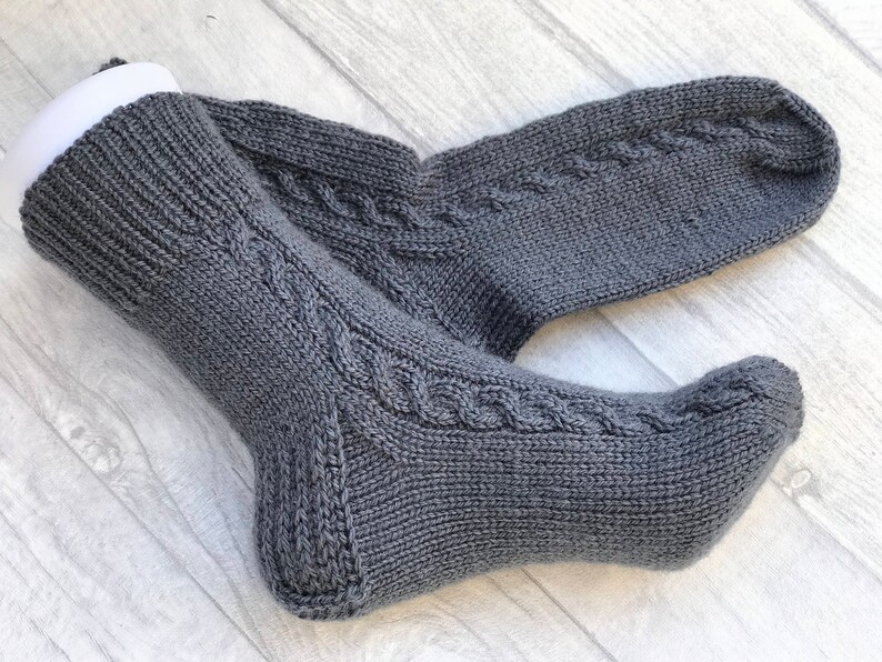 May include: A pair of gray knitted socks with a cable knit pattern.