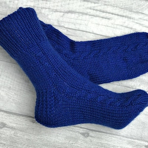 May include: A pair of blue knitted socks with a cable knit pattern.
