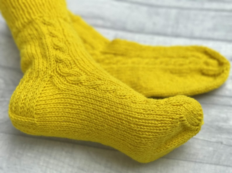 May include: A pair of yellow knitted socks with a cable knit pattern.