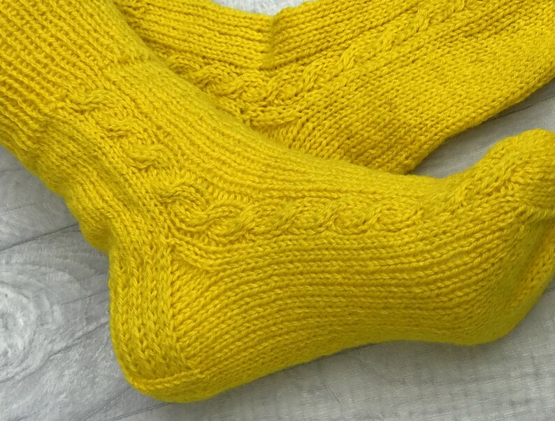May include: A pair of yellow knitted socks with a cable knit pattern.