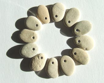 May include: A collection of 10 smooth, light brown stones with a hole drilled through each one. The stones are arranged in a circle, creating a decorative pattern.