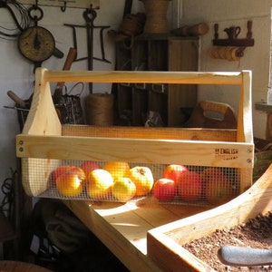 May include: A wooden carrying basket with a wire mesh insert, filled with red apples. The basket has a handle and is labeled "My English Garden".