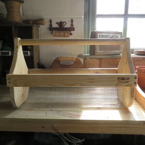 May include: A wooden gardening tool caddy with a wire mesh insert. The caddy has a handle and is labeled "An English Country Life".
