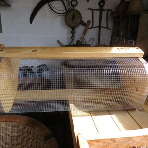 May include: A wooden and wire cage with a curved top and a wooden base. The cage is made of natural wood and has a wire mesh on the front and sides.
